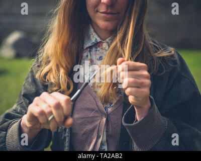 Eine junge Frau ist schneiden ihr Haar und Spliss im Freien Stockfoto