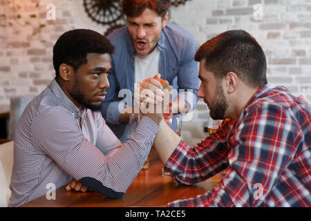 Herausforderung. Diverse Freunde Arm Wrestling an der Bar Stockfoto