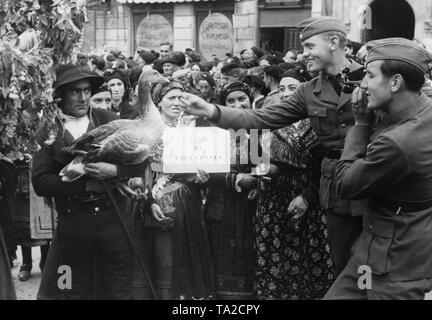 Foto von Feiern zu Ehren der Legion Condor und spanischen nationalen Verbände in der festlich geschmückten Straßen von Ciudad de Leon, Kastilien und Leon, am 22. Mai 1939. Ein Landwirt in einem traditionellen Kostüm präsentiert eine Gans zu zwei Soldaten. Zusätzlich zu einer Parade, eine traditionelle Trachtenumzug war auch organisiert. Wurde ein Triumphbogen zu Ehren der Legion eingeweiht. Stockfoto