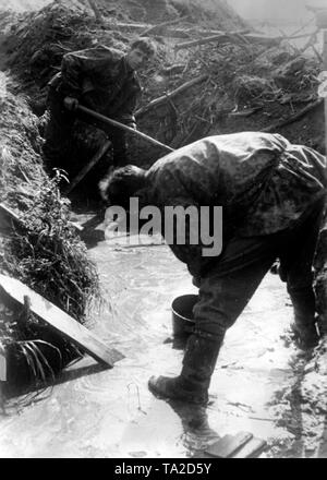 Deutsche Soldaten graben Sie einen Graben. Aufgrund der Niederschläge und den sumpfigen Boden auf die Leningrader Front, die Soldaten kämpfen, Schlamm, Wasser und Moskitos. Foto der Propaganda Firma (PK): SS Kriegsberichterstatter Krauss. Stockfoto