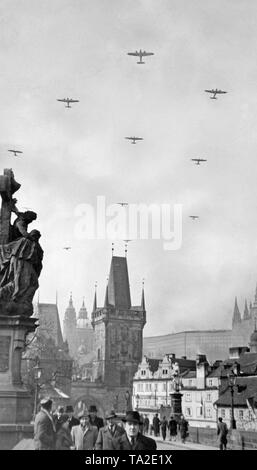 Heinkel He 111 deutsche Bomber fliegen über Prag. Die Passanten überqueren Sie die Karlsbrücke. Die erste slowakische Republik wurde auf Hitlers Befehl im März 1939 gegründet, und Böhmen und Mähren wurden von der Wehrmacht besetzt. Stockfoto