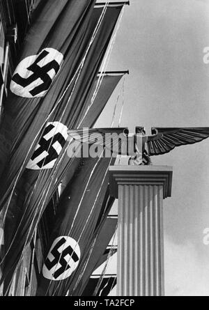 Hakenkreuzfahnen und einen Reichsadler mit Hakenkreuz auf eine Spalte in der "Aufmarsch der schaffenden Bevoelkerung der Reichshauptstadt" ("Deployment der Erstellung Bevölkerung der kaiserlichen Hauptstadt") Unter den Linden auf dem "Feiertag des deutschen Volkes" (Tag der Arbeit). Stockfoto