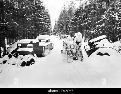 Deutsche Soldaten im Winter Kleidung Laufwerk auf ein kleines Kettenkrad (Half-track Motorrad) Typ HK 101 (Sd.Kfz. 2) Auf einer verschneiten Straße an der Ostfront. Nach links und rechts, mehr Schnee-bedeckten und wahrscheinlich zerstört. Foto der Propaganda Firma (PK): kriegsberichterstatter Schroeter. Stockfoto