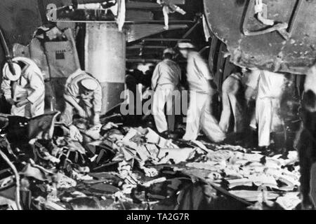 Foto von Seeleuten während einer Reinigung und den Betrieb auf dem Deck der 'Deutschland' nach dem Bombenanschlag auf den Port der balearischen Insel Ibiza auf den 29. Mai 1937. Im Vordergrund Trümmer liegt. Auf der Oberseite gibt es erschüttert Panzerplatten. Stockfoto