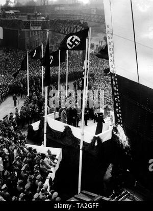 Hedwig Gustloff (rechts), Witwe des ermordeten Schweizer Landesgruppenleiter (national Group Leader), Wilhelm Gustloff, tauft das neue Schiff von der NS-Organisation "Kraft durch Freude" mit dem Namen ihres Mannes auf den Rumpf an der Blohm und Voss in Hamburg. Dahinter von Links nach Rechts: Adolf Hitler, Robert Ley, Erich Raeder und Karl Kaufmann. Ganz rechts Fotograf Heinrich Hoffmann. Stockfoto