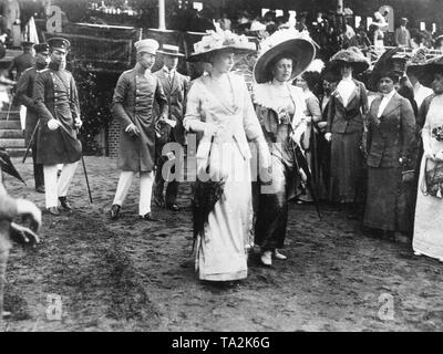 Kronprinz Wilhelm (3. von links mit dem Fernglas in der Hand) besucht eine Pferderennbahn in Ruhleben mit seiner Frau Cecilie (vorne links) und seine Schwester, Sophie Charlotte von Oldenburg (vorne rechts). Stockfoto