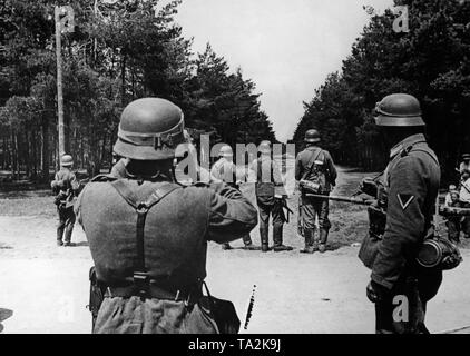 Soldaten einer Deutschen Advance Party sind auf der Suche nach dem Feind an einem Scheideweg. Auf der rechten Seite, russischen Zivilisten beobachten die Szene. Stockfoto