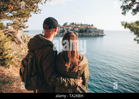 Ein junges Paar von Touristen bewundert die schöne Aussicht auf das Meer und die Insel Sveti Stefan in Montenegro. Stockfoto