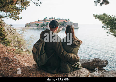 Ein junges Paar von Touristen bewundert die schöne Aussicht auf das Meer und die Insel Sveti Stefan in Montenegro. Stockfoto