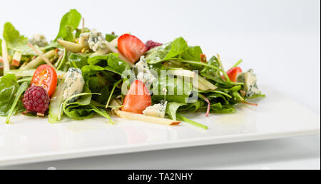 Grüner Salat mit Gorgonzola und Beeren auf einem weißen Teller. Stockfoto