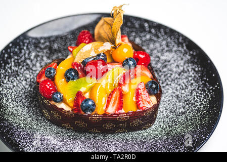 Herzförmige Frucht Biskuitteig, Obstkuchen auf schwarze Platte bestreut mit Puderzucker. Gesunde Süßwaren Hintergrund. Stockfoto