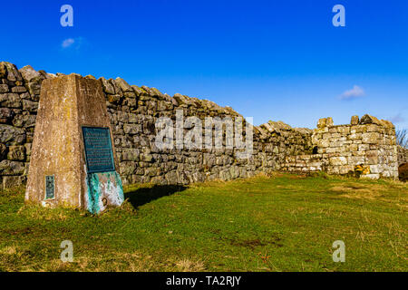 Trig Point auf dem Gipfel der Ros-Hügel, mit Plakette markiert den Standort der Ros Schloss Eisenzeit Hill fort. In der Nähe von chillingham, Northumberland, Großbritannien. November 2018. Stockfoto