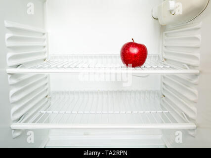 In hellen, frischen roten Apfel auf dem Regal der offenen leeren Kühlschrank. Gewichtsverlust Diät Konzept. Stockfoto