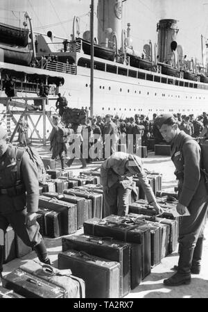 Foto von deutschen Soldaten der Legion Condor während der Rückfahrt an der Kaimauer im Hafen von Vigo, Galicia am 30. Mai 1939. Im Hintergrund die Kraft durch Freude ('Stärke durch Freude') Steamboat (KdF-Flotte), "die Deutschen" ("Bremer Vulkan", 1924, zuvor der "Sierra Morena"), war der spanische Kämpfer mit nach Hause zu nehmen. An der Front, das Gepäck der Soldaten. Stockfoto