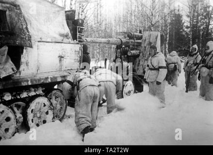 Deutsche Soldaten reparieren Sie die Ketten einer Zugkraftwagen (schweres Halbkettenfahrzeug Fahrzeug, vermutlich Sd.Kfz. 8/schwere Zugkraftwagen) an der Ostfront. Er zieht eine Pistole (8,8 cm Flak) durch den Schnee im Gebiet Brjansk. Foto der Propaganda Firma (PK): kriegsberichterstatter Henisch. Stockfoto