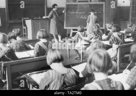 Blick in die Klassenzimmer während einer Schule Lektion für Mädchen in einem Berliner Waisenhaus, vermutlich im Jahre 1931. Eine Schülerin steht vor und schreibt mit Kreide auf die Tafel "Kaiser Wilhelm I.", auf dem Board ist schon geschrieben "Reichsgruendungsfeier [...] 1871' (Grundsteinlegung des Reiches). Stockfoto