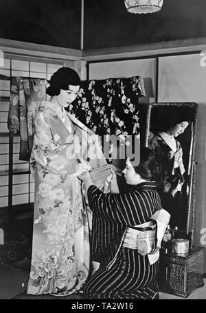 Ein Knecht hilft, eine junge Frau in Japan auf ihrem Kimono zu setzen. (Undatiertes Foto, C. 1940 s) Stockfoto
