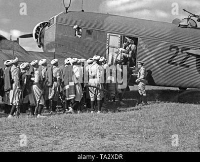 Das Foto zeigt die marokkanische Soldaten der spanischen Fremdenlegion mit einem deutschen Junkers Ju 52 Transportflugzeuge mit der Lackierung der Deutschen Legion Condor. Die Soldaten wurden von Tetouan, Spanish-Morocco, Afrika zu fliegen, auf dem Spanischen Festland im Sommer 1936. Auf der rechten Seite an der Oberseite, die On-board-Waffe (MG 34) gegen feindliche Kämpfer. Nach dem Ausbruch des Spanischen Bürgerkrieges am 27. Juli 1936 übermittelte Deutschland militärische Unterstützung für General Franco (Operation Feuerzeauber). Zusätzlich wurden 20 Ju-52 s (meist Lufthansa Flugzeuge) wurden bereitgestellt, die flogen mehr als 800 Flüge von Stockfoto