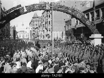 Foto einer Siegesparade der Spanischen Truppen und die Deutsche Legion Condor zu Ehren von General Francisco Franco im festlich geschmückten Straßen von Ciudad de Leon, Kastilien und Leon am 22. Mai 1939. Die Soldaten marschieren in zwei Richtungen: Auf der linken Seite eine Einheit der spanischen Guardia Civil ist paradieren auf der Rechten die Legion Condor. Im Hintergrund, der Triumphbogen zu Ehren der Legion Condor. Stockfoto