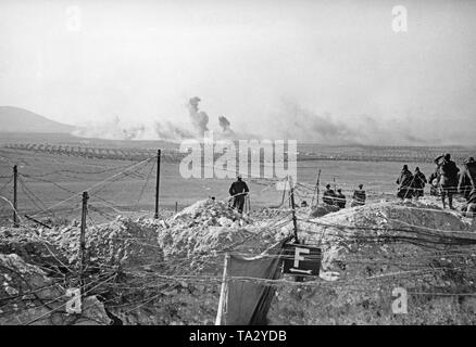 Foto während der letzten spanischen nationalen Offensive in Toledo, Kastilien-La Mancha, Spanien, Ende März, 1939. In den Vordergrund, eine Uhr post von Stacheldraht mit Soldaten der Schlacht gesichert. Hinter, Spalten der Infanterie, wie sie März vorwärts durch die Olivenhaine. Am Horizont: waberndem Rauch durch die Artillerie Feuer verursacht. Stockfoto