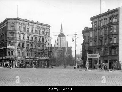 Ansicht des Bluecherplatz und die Bluecherstrasse in Berlin. Im Hintergrund der Heilig Kreuz Kirche. Auf dem Gebäude nach Links sind Werbeanzeigen für die Berliner Kindl, Victoria Versicherung und Carl Richard Schmidt. Rechts im Bild ist ein Hinweisschild an der Autobahn. Stockfoto