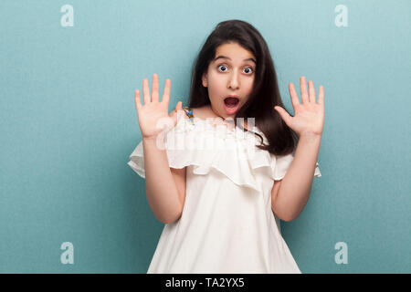 Portrait von schockiert oder Angst schöne Brünette junge Mädchen mit langen schwarzen glatten Haaren in weißem Kleid mit hand Block und Kameras Stockfoto