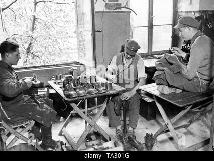 Mitglieder der Freiwilliger Arbeitsdienst - Freiwillige Arbeit Service (FAD) Reparatur Schuhe und eine Jacke (Undatiertes Foto). Stockfoto