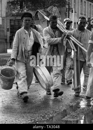 Häftlinge im KZ Dachau März mit Spaten, Schaufeln und Eimer. Dieses Bild, wie viele andere, war für die NS-Propaganda gemacht. Stockfoto