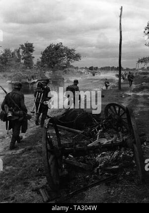 Deutsche Infanterie und Sturmgeschütze auf dem Vormarsch in der Ukraine. Die 2. und 3 Soldaten von der linken tragen eine zerlegt 34 Granatwerfer Granatwerfer. Stockfoto