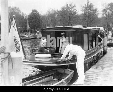 Kronprinz Wilhelm von Preußen (links sitzend) mit seiner Frau Kronprinzessin Cecilie von Mecklenburg auf einem Boot auf der Havel. Ein Seemann steht auf dem Dock, wo das Schiff gesichert ist und unmooring. Stockfoto