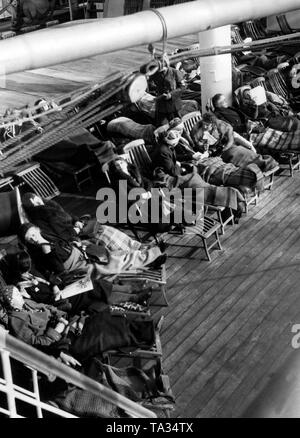 Urlauber in Liegestühlen, lesen Zeitungen und Bücher und Reden an Bord des Kreuzfahrtschiffes t entspannen. Louis' der NS-Organisation "Kraft durch Freude". Stockfoto