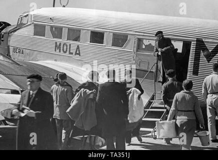 Foto eines deutschen Junkers Ju 52 der spanischen Fluggesellschaft Iberia 1939 am Flughafen von Salamanca, Kastilien und Leon, Spanien, durch die Fenster des neuen Terminals. Soldaten und Zivilisten sind, wenn Sie aus dem Flugzeug. Die Maschine ist 'Mola' benannt, nach General Emilio Mola Vidal (gestorben 1937), einer der Führer des Aufstandes von General Francisco Franco. Während des Bürgerkriegs, die Deutsche Lufthansa und die Iberia (gegründet 1927) durchgeführten Flüge meist mit deutschen Piloten in den Spanischen Nationalen Zone ab 1937 geplant. Die Flugzeuge wurden von der Deutschen Lufthansa AG zur Verfügung gestellt. Stockfoto