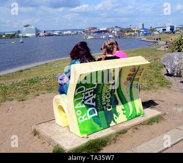 Besucher sitzen auf der Roald Dahl der enormen Krokodil "Sitzbank in Cardiff Bay, Wales, UK in 2019. Stockfoto