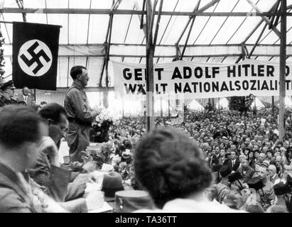 Hitler hielt eine Rede, in einem Münchner Biergarten Zelt während der Wahlkampagne. Ein Banner für die Stimmabgabe für Adolf Hitler genannt wird, und einen Appell für die Nationalsozialisten zu stimmen. Stockfoto