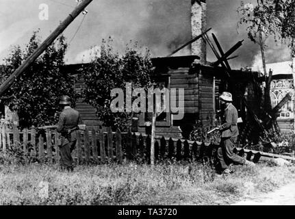 Deutsche Soldaten suchen Sie ein brennendes Dorf für sowjetische Soldaten am nördlichen Sektor der Ostfront (vermutlich in Litauen oder in nördlichen Belarus). Im Laufe der Operation Bagration, der Roten Armee Truppen der Wehrmacht nach Westen im Sommer 1944. Nur gelegentlich können einzelne Positionen, wie ein Dorf, von der Wehrmacht für kurze Zeit gehalten werden. Foto der Propaganda Firma (PK): kriegsberichterstatter Weber. Stockfoto