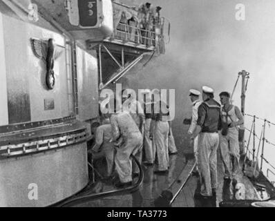 Foto von einer Gruppe von Seeleuten während der Reinigung- und Löscharbeiten auf dem Deck der 'Deutschland' nach dem Bombenanschlag auf den Port der balearischen Insel Ibiza auf den 29. Mai 1937. Auf der linken Seite des vorderen Stoßdämpferdoms (mit Reichsadler und Hakenkreuz eingerichtet). Im Hintergrund und waberndem Rauch. Stockfoto