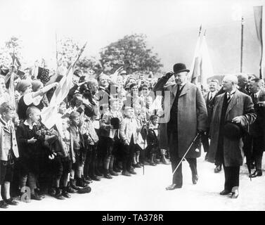 Paul von Hindenburg (links) von der Bayerische Ministerpräsident Heinrich Held (rechts) bei seiner Ankunft in Kochel, wo er von der Dorfjugend mit weißen und blauen Fahnen begrüßt wird begleitet. (Undatiertes Foto) Stockfoto