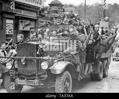 Die Menschen erhalten, die sich zurückziehenden deutschen Truppen in Karlsbad (Karlovy Vary) Heute am 4. Oktober 1938. Einige Kinder haben auf einem Lastwagen geklettert und begleiten Sie dabei. Der Stapler ist mit Blumen geschmückt. Stockfoto
