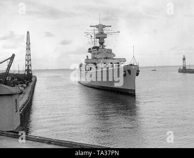 Foto der teilweise zerstörten Heavy Cruiser 'Deutschland' bei der Einfahrt in den Hafen von Wilhelmshaven an der Nordsee im Juni 1937. Nach rechts und links, die Hafenanlagen. Stockfoto