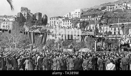 Foto einer Masse Gruß die Marching - Francisco de Borbón y de la Torre, Herzog von Sevilla (auf der Rückseite ein Pferd reiten, von 1882 bis 1953) Vor den Ruinen des Castillo Gibralfaro in Málaga, Andalusien, Spanien, im Jahre 1936. Im Vordergrund, Passanten begrüße ihn. Die Straße ist mit spanischen Flaggen dekoriert. Stockfoto