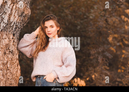 Smiling teenage Mädchen 17-18 Jahre alten tragen Strickpullover posiert im Freien. Mit Blick auf die Kamera. Herbst Saison. 20. Stockfoto