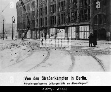 Im Zuge der Berliner Maerzkaempfe (März kämpft) und der Einsatz von Artillerie durch von der Regierung loyalen Truppen, viele Straßen und Häuser wurden im Zentrum von Berlin am Boden zerstört. Hier ist ein Foto von dem zerstörten Oberleitungen am Alexanderplatz. Auf der rechten Seite zwei Zivilisten sind in einem Gespräch mit einem Soldaten. Stockfoto