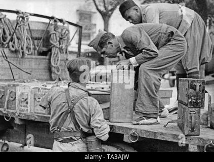 Während der Kämpfe für Talavera, in Toledo, Kastilien-La Mancha, ein Soldat der Franco Truppen Hände eine Schachtel Munition zu seinem Kameraden aus einem Lastwagen. Im Hintergrund, eine Spanische ausländische Legionär aus Marokko (Fuerzas Regulares Indigenas) gibt eine Hand. Der Soldat in der Mitte trägt einfache Baumwolle Schuhe mit geflochtenem Hanf Sohlen (sogenannte Alpargatas). Stockfoto