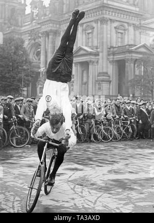 Zwei Fahrrad Akrobaten zeigen einen Stunt vor dem Publikum im Berliner Schloss im Rahmen der Feierlichkeiten zum "Tag des Radfahrers' ('Day des Radfahrers"). Im Hintergrund der Berliner Dom. Stockfoto