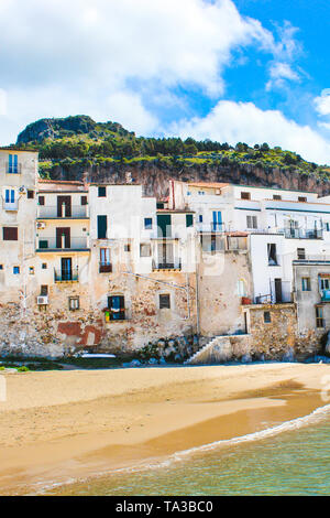 Schöne alte Häuser mit Blick auf das Tyrrhenische Meer in Cefalu, Sizilien, Italien. Auf der Vertikalen Bild mit Felsen hinter der historischen Stadt gefangen. Cefalu ist ein beliebtes Urlaubsziel. Stockfoto