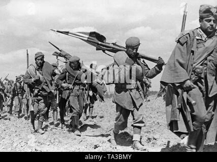 Foto von Soldaten eines Netzteil von Francos Truppen marschieren in Toledo, Kastilien-La Mancha Ende März, 1939. Die Soldaten marschieren und die regimental Standard und Fahnen tragen. Sie sind mit Karabiner bewaffnet. Im Frühjahr 1939 wurden die letzten Schlachten des Spanischen Bürgerkriegs statt, die offiziell mit dem Sieg der spanischen Staatsangehörigen am 1. April 1939 beendet. Stockfoto