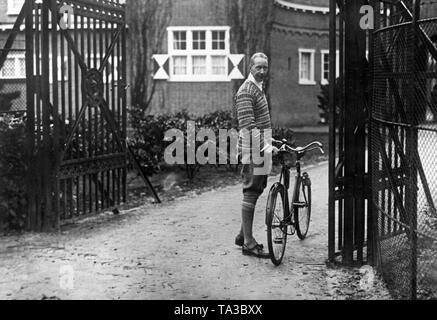 Der preußische Kronprinz (Mitte) sein Vater, der ehemalige Kaiserreich Wilhelm II., im Niederländischen Doorn besuchen. Anlass war der 67. Geburtstag des Kaisers, im Exil. Hier, Kronprinz Wilhelm steht mit seinem Fahrrad am Eingang zum Haus Doorn. Stockfoto