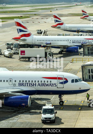 Der Flughafen London Gatwick, ENGLAND - April 2019: Vier British Airways jets am Flughafen Gatwick mit anderen Flugzeugen im Hintergrund geparkt Stockfoto