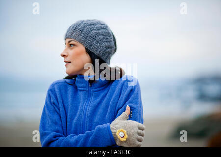 Junge Frau warme Kleidung tragen, während am Strand im Winter. Stockfoto