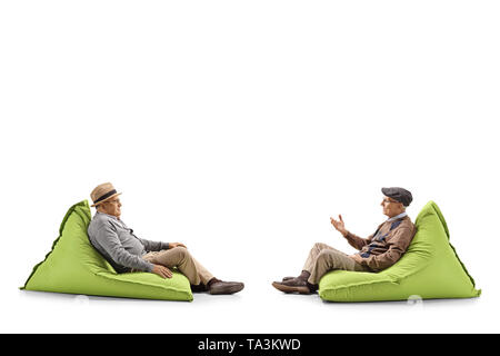 Volle Länge Profil Schuß von zwei ältere Männer sitzen auf sitzsäcken und ein Gespräch auf weißem Hintergrund Stockfoto